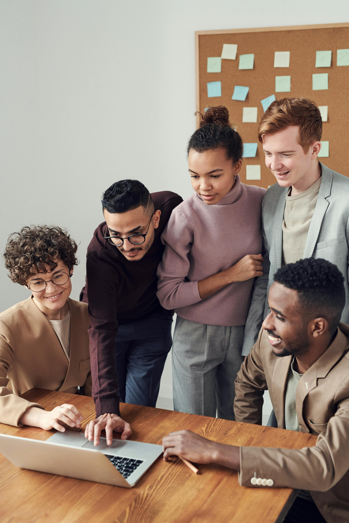 a group of people standing around a table looking at a laptop