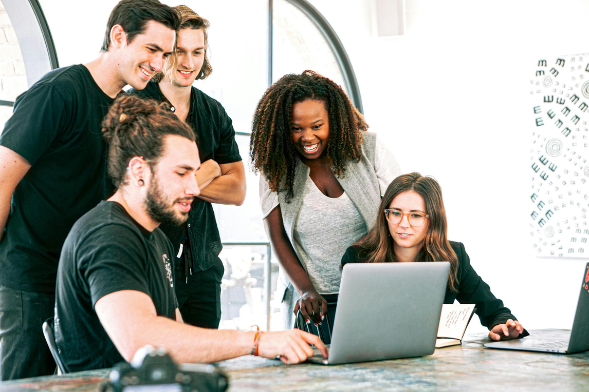 a group of people looking at a laptop together